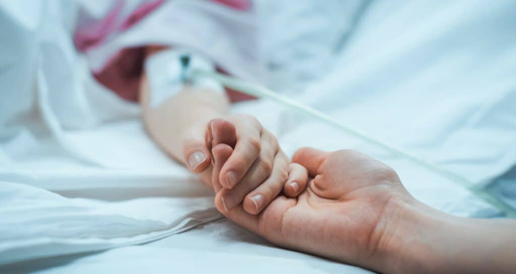 Honorararzt Gehalt – Arzt hält beruhigend Hand von Patientin im Krankenbett